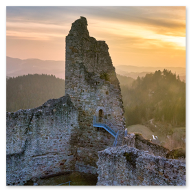 Panoramablick auf die mittelalterliche Burgruine Ruttenstein im Mühlviertel: teilrestaurierte Steinmauern und ein hoher Bergfried thronen auf einem bewaldeten Hügel, umgeben von sanften Wäldern. Die Szene ist in warmes Abendlicht getaucht, der Himmel leuchtet in goldgelben und orangefarbenen Tönen. Ideal für SEO-Stichworte wie Burg Ruttenstein, Mühlviertel, Burgruine, Landschaftsfotografie, Sonnenuntergang, Oberösterreich und historische Architektur.