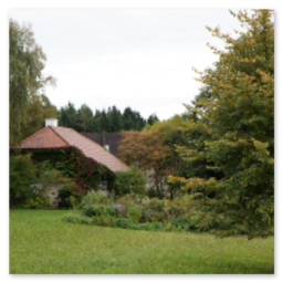 Wohnhaus mit rotem Dach inmitten eines Gartens entlang der Strecke Neumarkt–Unterweitersdorf, umgeben von Bäumen, Wiese und dichter Vegetation.