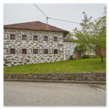 Traditionelles Steinbloßhaus mit rotem Ziegeldach, kleinen Fenstern und gepflegtem Vorgarten; vorgelagerte Steinmauer und ländliche Umgebung in Stiftung bei Neumarkt im Mühlviertel