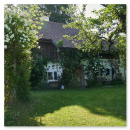 Landhaus mit weißer Fassade, Holzdetails und blühenden Kletterpflanzen entlang der Strecke Neumarkt–Unterweitersdorf, umgeben von Garten, Wiese und Bäumen.