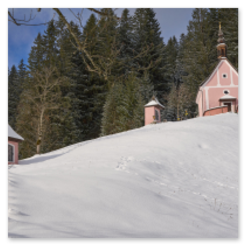 Verschneiter Hang mit Kapelle und zwei kleinen Bauwerken, Treppenaufstieg, Nadelwald im Hintergrund
