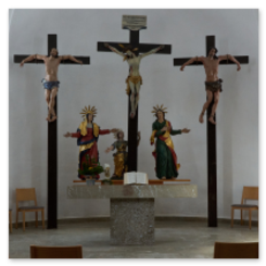 Innenraum mit drei Kreuzigungsdarstellungen, Altar mit Figuren und Buch, Holzstühle im Halbkreis