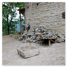 Holzseilzug an Steinmauer mit hölzernem Lastbehälter, Steinlager und Werkbank im Außenbereich der mittelalterlichen Baustelle in Friesach