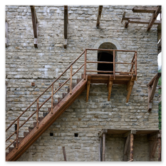 Steinbau mit Holzgerüst und schräger Holztreppe zu einem Rundbogenportal, Teil der mittelalterlichen Baustelle in Friesach