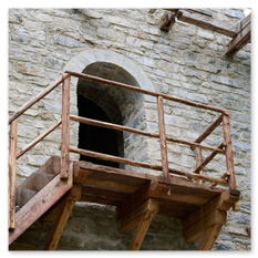 Holztreppe mit Geländer führt zu einem rundbogigen Eingang in einem Steinbau, Teil der mittelalterlichen Baustelle in Friesach