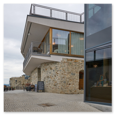 Moderne Gebäude mit Glasfassaden und Steinbasis, Außensitzbereich und gepflastertem Weg im Weingut Taggenbrunn