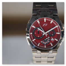 Sportlicher Chronograph mit rotem Zifferblatt, Metallarmband und F1-Logo, ausgestellt im Rahmen der Jacques-Lemans-Uhrenschau im Weingut Taggenbrunn