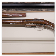 Ornamentierte Steinschlosspistole mit Metallintarsien auf weißem Sockel, Teil der historischen Sammlung im Museum der Burg Taggenbrunn