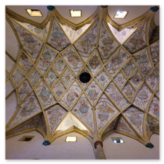 Decke mit Kreuzrippengewölbe und Fresken bei Maria Saal – goldverzierte Rippen, figurenreiche Felder und dunkles Zentrum, kunstvolle Raumspannung in sakraler Höhe.