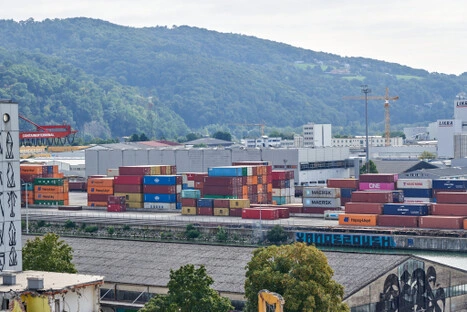 Gestapelte Frachtcontainer von Maersk, Hapag-Lloyd, ONE und Hamburg Süd im Hafenpark LINZ AG – industrieller Umschlagplatz mit ruhigem Blick auf Hügel und Kräne