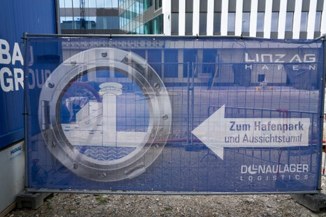 Banner mit maritimem Motiv und Richtungspfeil zum Aussichtsturm; verbindet grafische Klarheit mit urbaner Orientierung im Übergang zwischen Industrie und Freizeit.